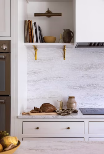 A kitchen with a full height backsplash, made with Cambria quartz in the color Ironsbridge.